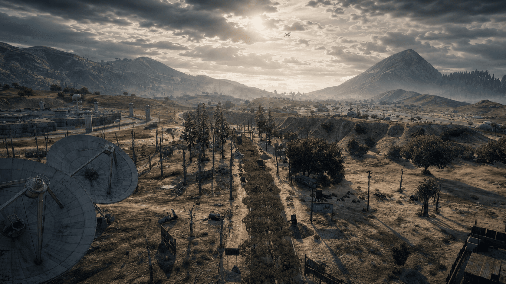 Desert valley with satellite dishes and prison outpost at dusk